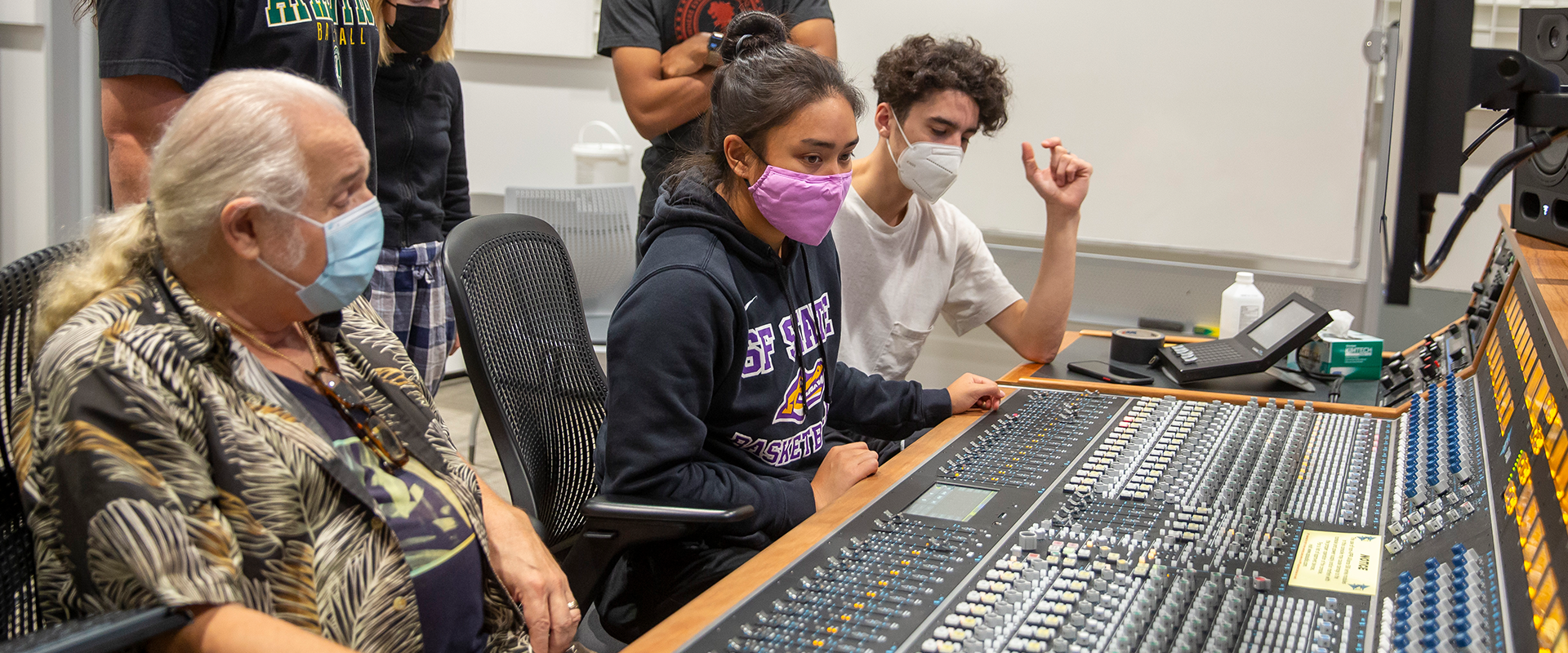 Students learning how to use an audio mixer.